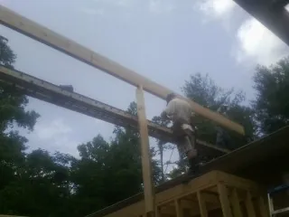 Carpenter setting a ridge beam over a new addition frame — Ice Dam Removal by Roofing Brothers in Keezletown