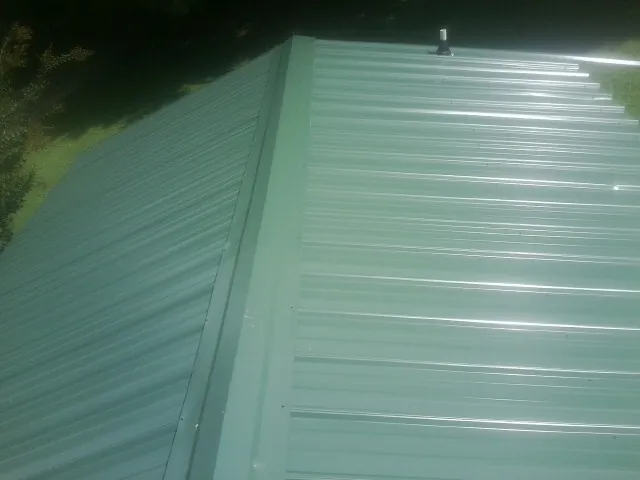 New green metal panels meeting at the ridge of a roof — Flat Roof Repair work by our crew in Keezletown