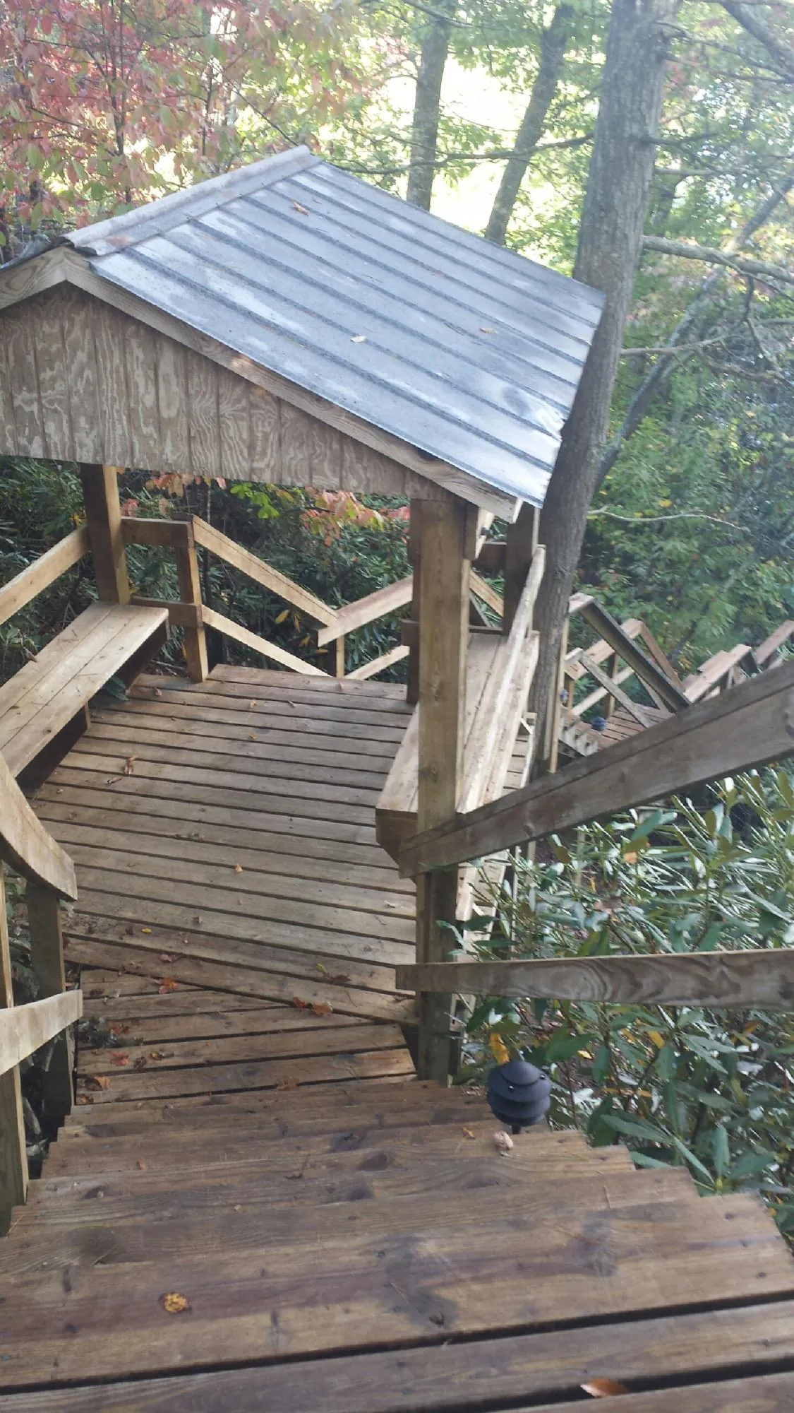 Metal roofed shelter over wooden steps on a wooded walkway — Skylight Repair & Installation work by our crew in Keezletown