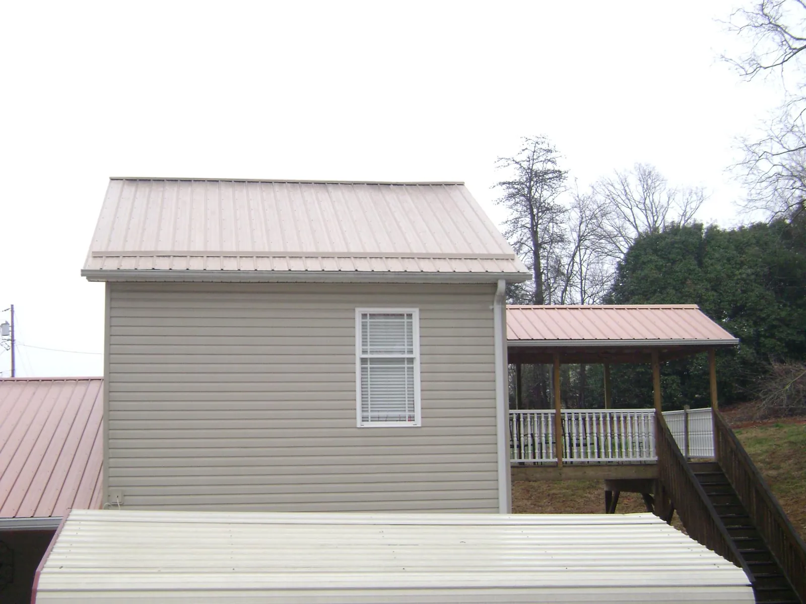 Tan metal roofs on a two story addition and attached porch, from a Roof Replacement job in Keezletown