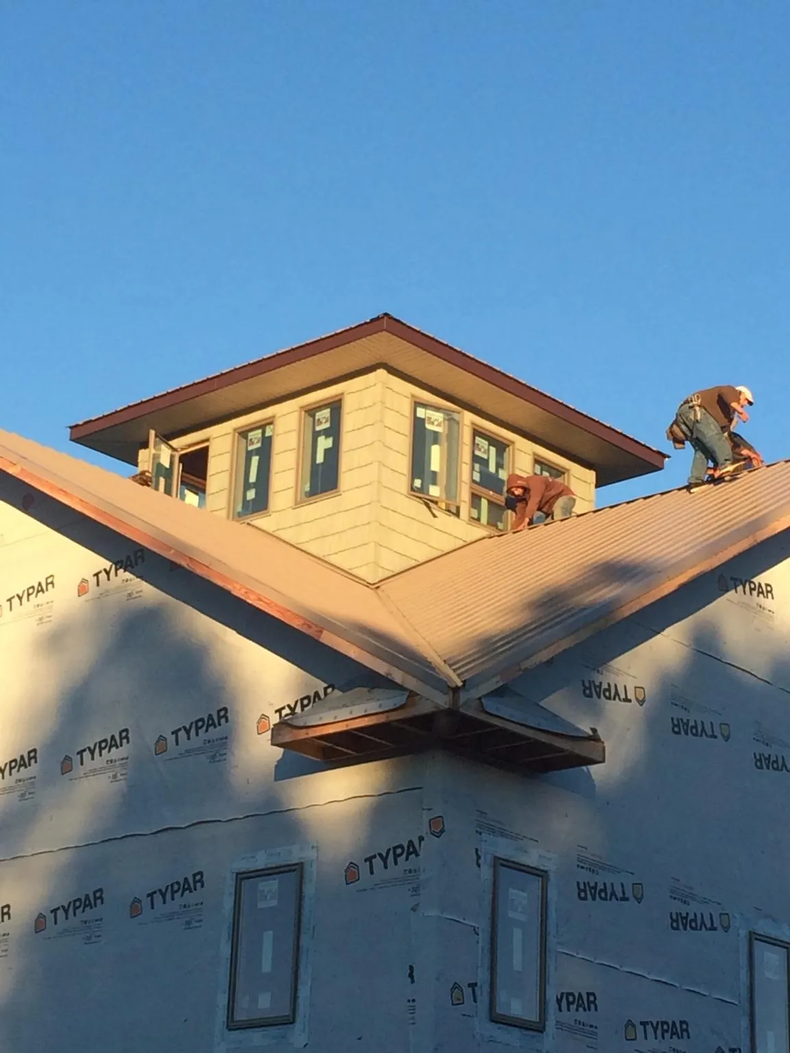 Roofers working around a rooftop cupola on a new metal roof at sunset — Roof Waterproofing in Keezletown by Roofing Brothers